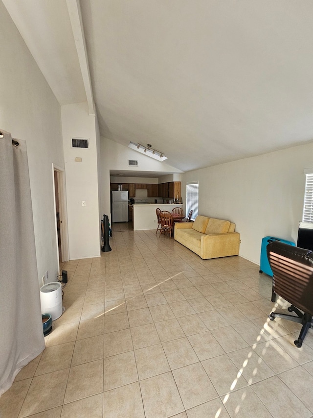 living room with vaulted ceiling with beams and light tile patterned flooring