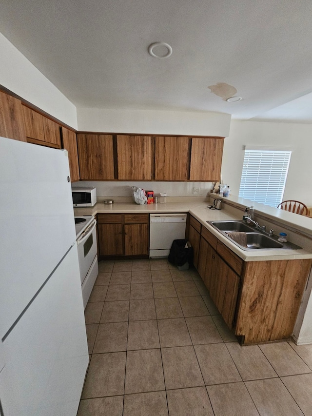 kitchen featuring kitchen peninsula, sink, light tile patterned floors, and white appliances