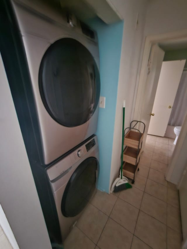 laundry room featuring stacked washer and dryer and light tile patterned floors