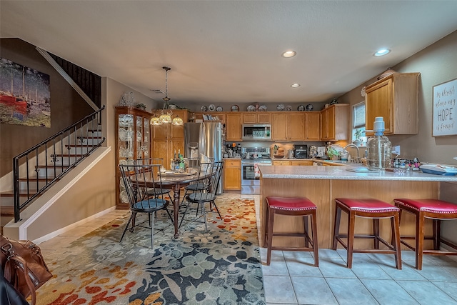 kitchen with kitchen peninsula, light tile patterned floors, a breakfast bar area, stainless steel appliances, and decorative light fixtures