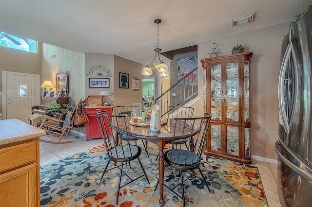 tiled dining space featuring a textured ceiling and a chandelier