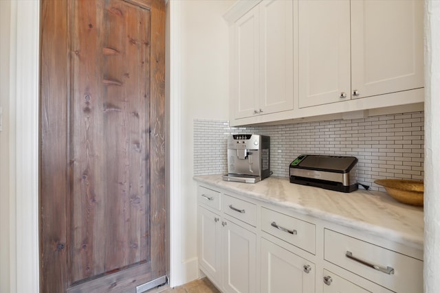 kitchen with white cabinets, tasteful backsplash, and light stone countertops