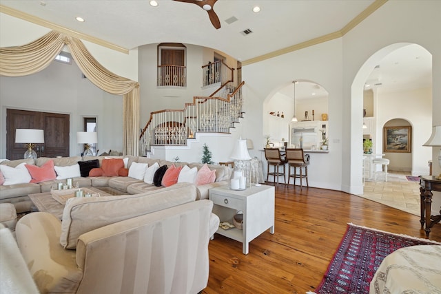 living room featuring wood-type flooring, crown molding, and a high ceiling