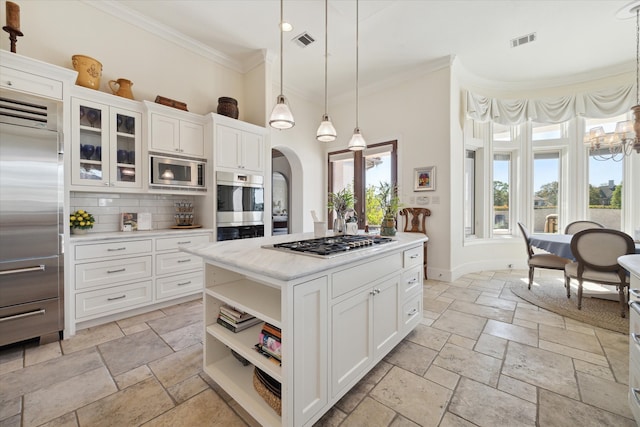 kitchen featuring appliances with stainless steel finishes, ornamental molding, decorative light fixtures, a center island, and white cabinetry