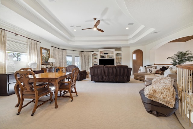 carpeted dining space with a raised ceiling, ceiling fan, a healthy amount of sunlight, and ornamental molding