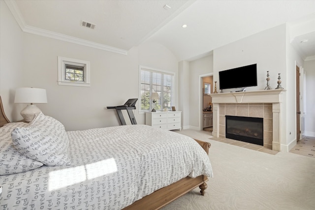 carpeted bedroom with ensuite bathroom, a tiled fireplace, and multiple windows