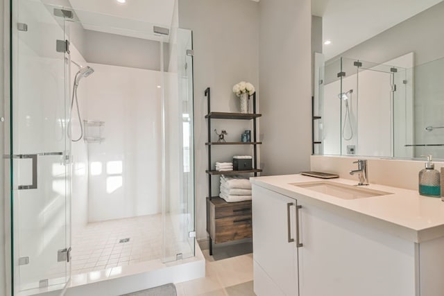 bathroom with a shower with door, tile patterned floors, and vanity