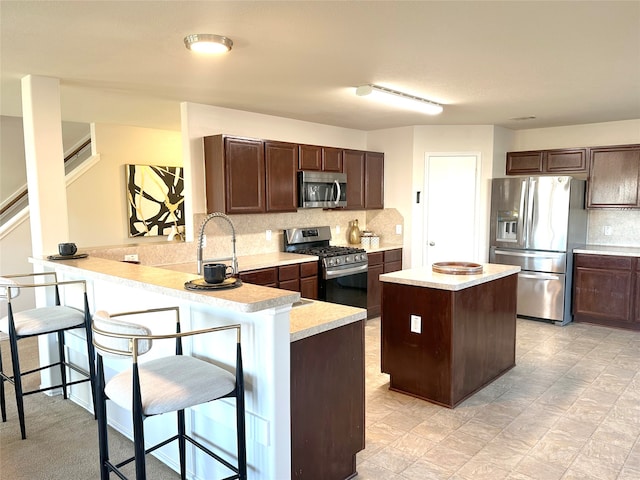 kitchen featuring sink, kitchen peninsula, a breakfast bar area, dark brown cabinetry, and stainless steel appliances