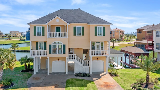 view of front of property with a front yard, a garage, a water view, and a balcony