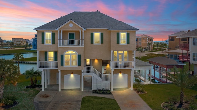 coastal home featuring a water view, a garage, a lawn, and a balcony