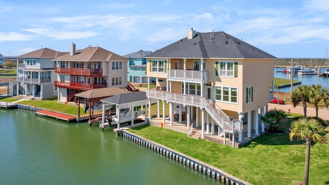 rear view of property featuring a water view, a balcony, and a yard