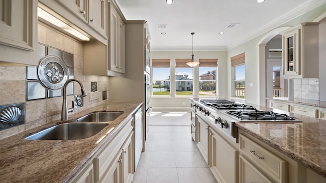 kitchen featuring tasteful backsplash, sink, stainless steel appliances, decorative light fixtures, and crown molding