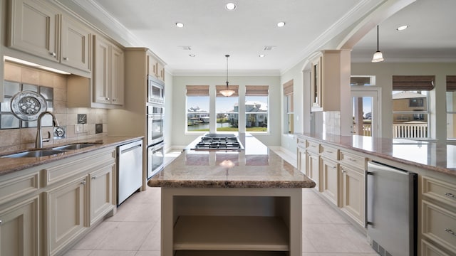 kitchen featuring appliances with stainless steel finishes, a center island, pendant lighting, and cream cabinets