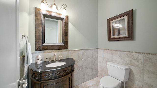 bathroom with vanity, toilet, and tile walls