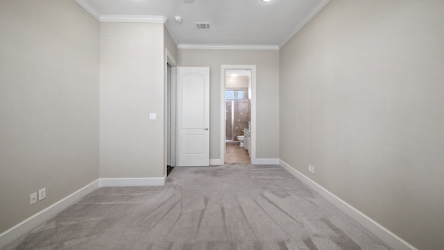 unfurnished bedroom featuring crown molding, ensuite bathroom, and light colored carpet