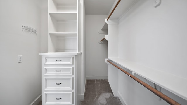 walk in closet with dark colored carpet