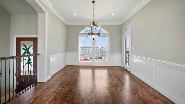 unfurnished dining area with crown molding, dark hardwood / wood-style floors, a chandelier, and a water view