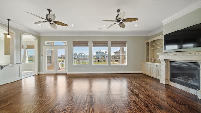 unfurnished living room featuring ornamental molding, a healthy amount of sunlight, a tiled fireplace, and dark wood-type flooring