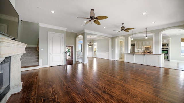 unfurnished living room featuring ceiling fan, ornamental molding, and dark hardwood / wood-style floors