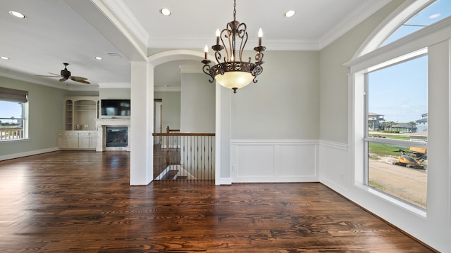 unfurnished dining area featuring ceiling fan with notable chandelier, ornamental molding, and dark hardwood / wood-style floors