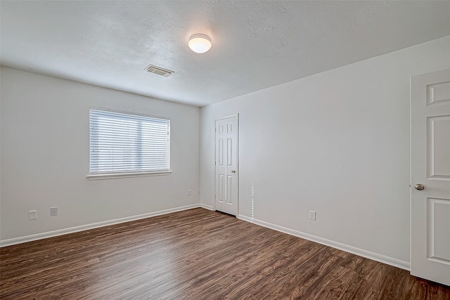 empty room featuring a textured ceiling and dark hardwood / wood-style flooring