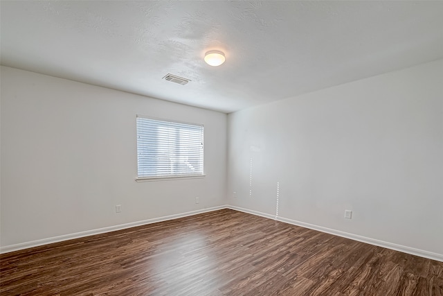 spare room featuring a textured ceiling and dark hardwood / wood-style floors