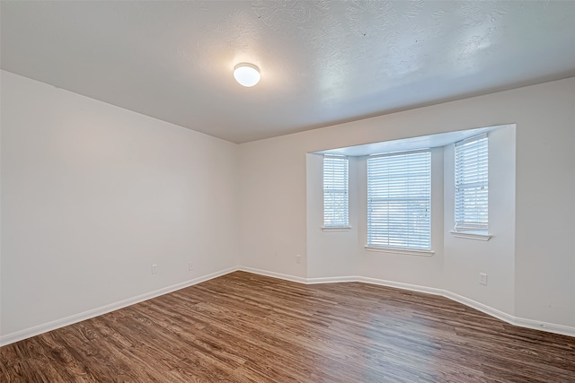 unfurnished room featuring a textured ceiling and dark wood-type flooring