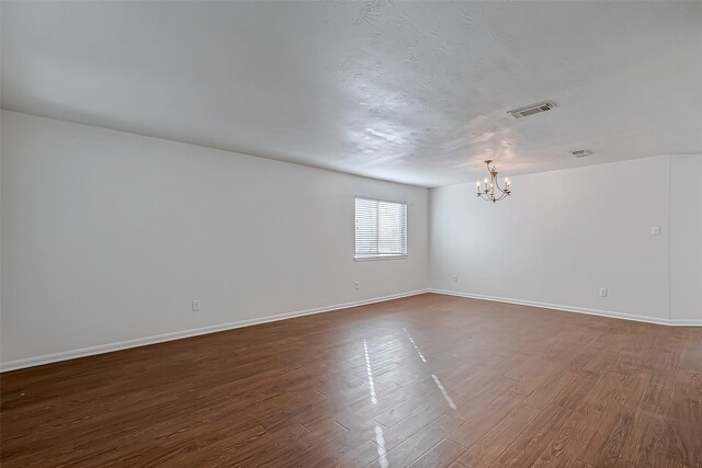 spare room featuring dark hardwood / wood-style floors and a notable chandelier