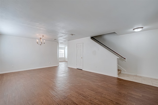 unfurnished living room with wood-type flooring and an inviting chandelier