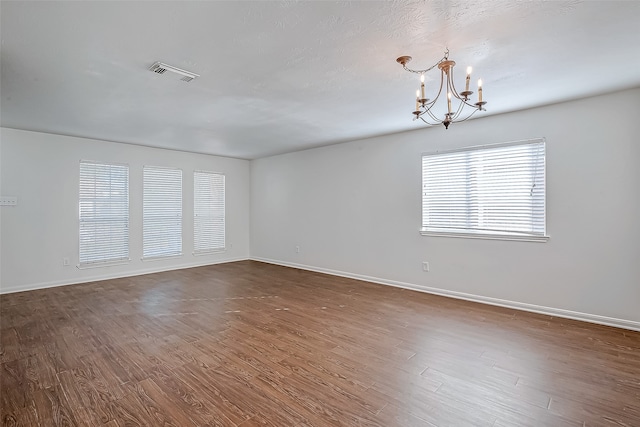 empty room featuring a chandelier and dark hardwood / wood-style floors