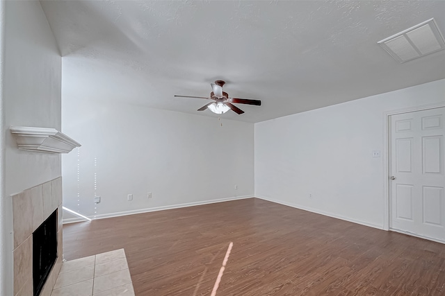 unfurnished living room with ceiling fan, wood-type flooring, and a fireplace