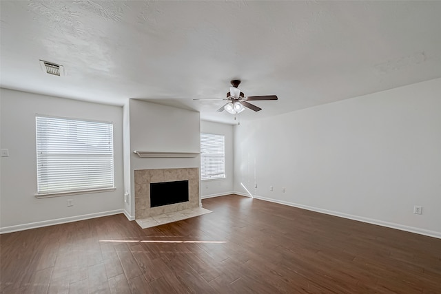 unfurnished living room with dark hardwood / wood-style floors, ceiling fan, and a tile fireplace