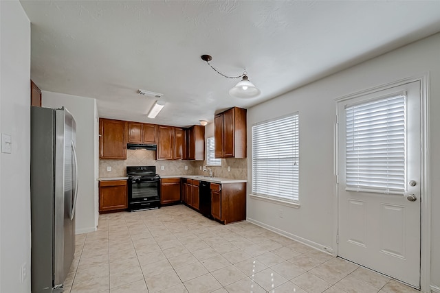 kitchen featuring black appliances, decorative light fixtures, sink, and a wealth of natural light