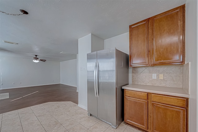 kitchen with ceiling fan, stainless steel fridge, light wood-type flooring, a textured ceiling, and tasteful backsplash