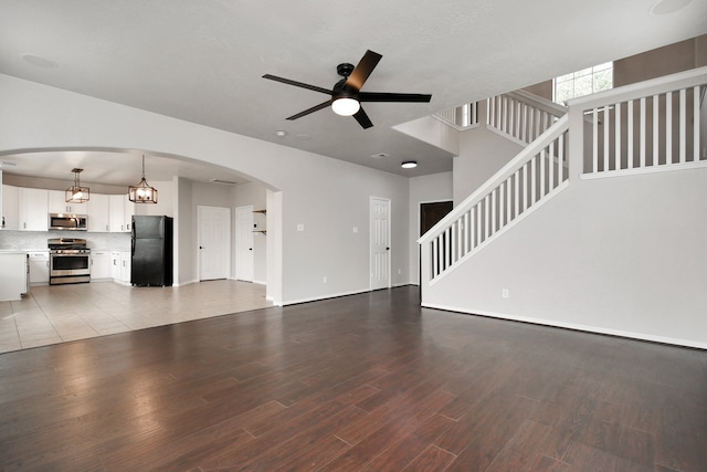 unfurnished living room featuring hardwood / wood-style floors and ceiling fan with notable chandelier