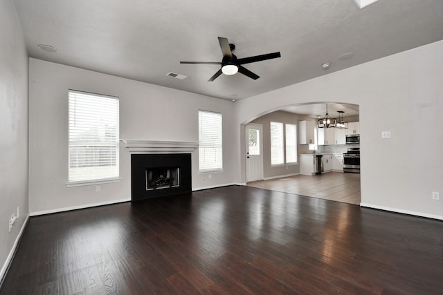 unfurnished living room featuring a textured ceiling, wood-type flooring, and ceiling fan with notable chandelier