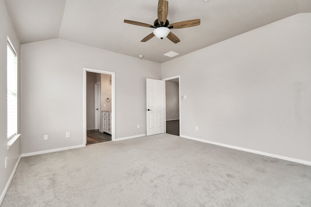 unfurnished bedroom with carpet flooring, connected bathroom, vaulted ceiling, and ceiling fan