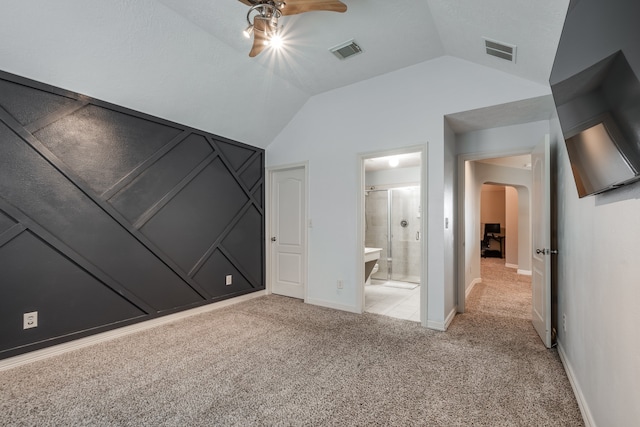 unfurnished bedroom with ceiling fan, ensuite bathroom, light carpet, and vaulted ceiling