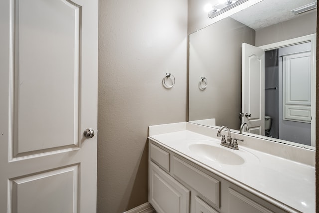 bathroom featuring a textured ceiling, vanity, and toilet