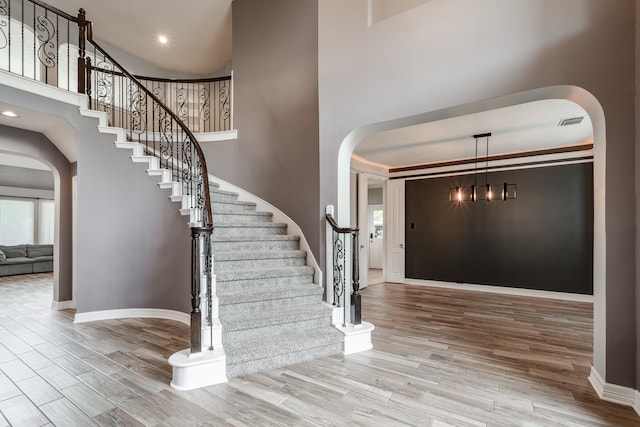 entrance foyer with wood-type flooring, a towering ceiling, and ornamental molding