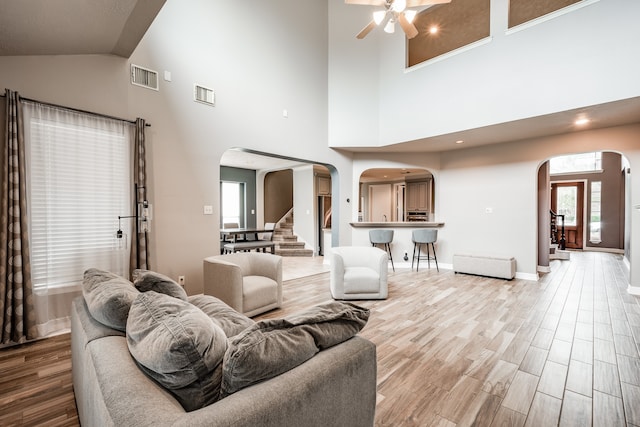 living room with high vaulted ceiling, light hardwood / wood-style flooring, and ceiling fan