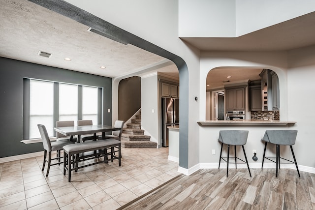 dining space with light wood-type flooring and a textured ceiling