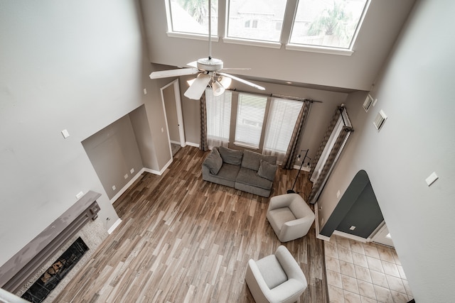 living room with ceiling fan, light hardwood / wood-style flooring, and a towering ceiling