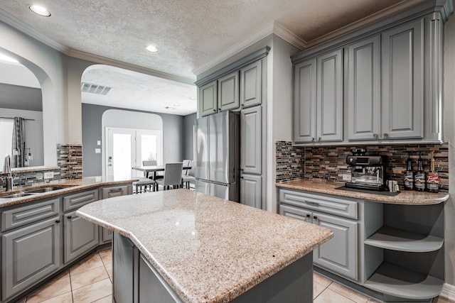 kitchen featuring stainless steel refrigerator, decorative backsplash, a kitchen island, and a textured ceiling