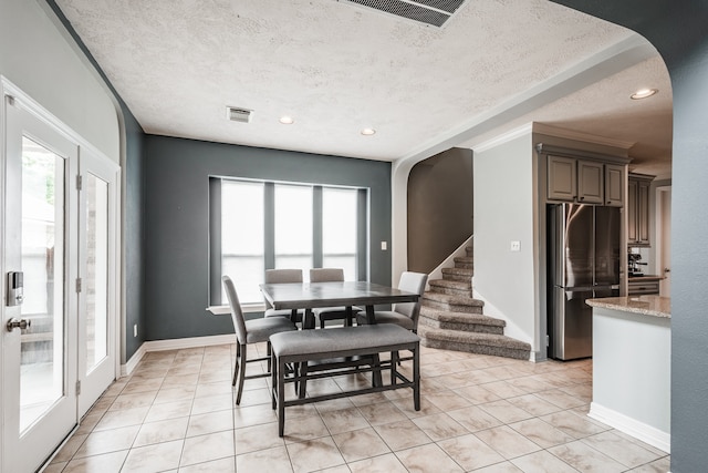 tiled dining room featuring crown molding and a textured ceiling