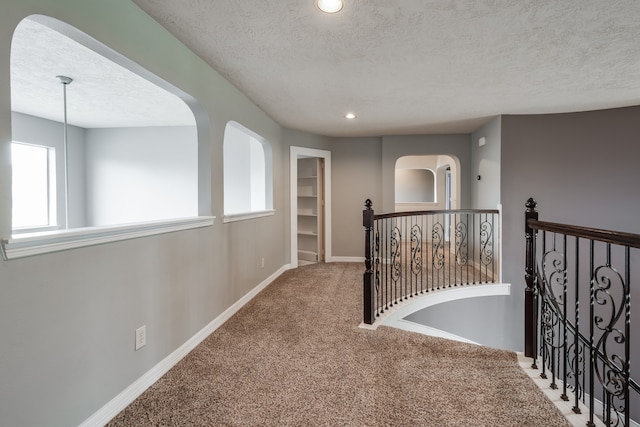 corridor with carpet flooring and a textured ceiling