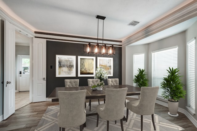 dining space with wood-type flooring, ornamental molding, and a notable chandelier