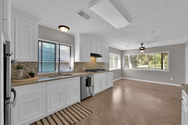 kitchen with white cabinets, light tile patterned floors, appliances with stainless steel finishes, backsplash, and sink