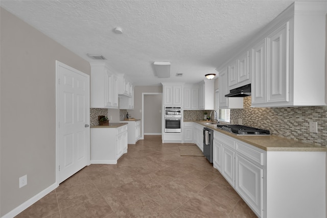 kitchen with decorative backsplash, white cabinets, appliances with stainless steel finishes, a textured ceiling, and sink