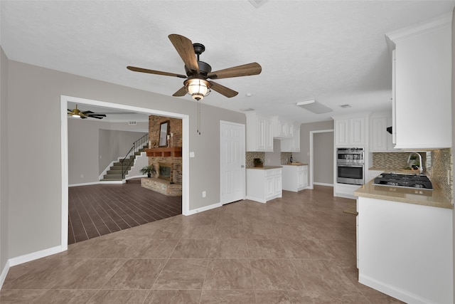 kitchen featuring stainless steel double oven, white cabinetry, backsplash, and gas cooktop